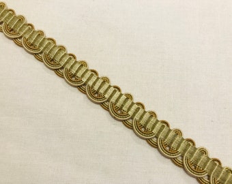 May include: A close-up of a beige and brown decorative trim with a looped design. The trim is made of woven fabric and has a subtle sheen.