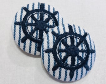May include: Two blue and white striped fabric buttons with a navy blue embroidered ship's wheel design.