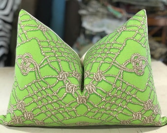 May include: A green throw pillow with a white border features a pattern of beige rope knots and a woven rope design.