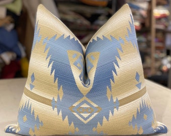 May include: A blue and beige patterned throw pillow with a geometric design. The pillow is made of a soft, woven fabric.