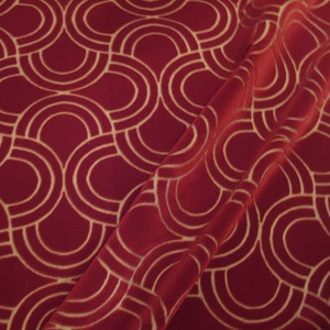 May include: Red fabric with a gold geometric pattern of overlapping circles and arches.
