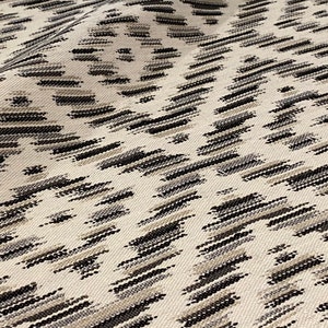 May include: White fabric with a black and gray geometric pattern. The pattern is a repeating diamond shape with a subtle ikat design.