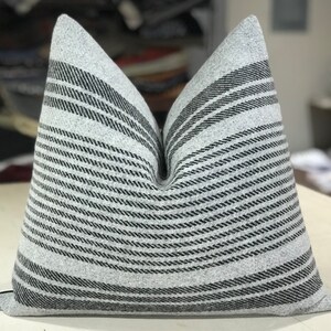 May include: A gray and black striped throw pillow with a soft, textured fabric. The pillow is rectangular and has a subtle sheen.