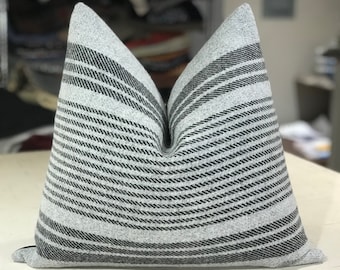 May include: A gray and black striped throw pillow with a soft, textured fabric. The pillow is rectangular and has a subtle sheen.