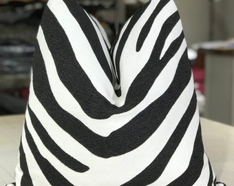May include: Black and white zebra print throw pillow. The pillow is made of a soft, textured fabric.