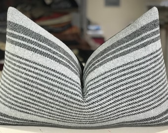 May include: A gray and black striped pillow with a subtle sheen. The pillow is made of a soft, textured fabric and has a simple, modern design.