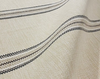May include: Close-up of a beige fabric with black stripes. The fabric has a woven texture and is soft to the touch.