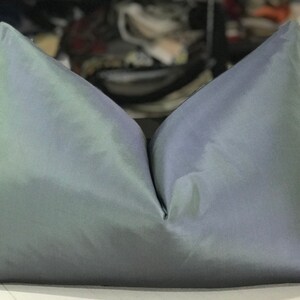 May include: A soft, iridescent pillow with a light blue and green color gradient. The pillow is made of a smooth, silky fabric and has a simple, rectangular shape.