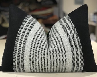 May include: Black and white striped throw pillow with black fabric trim. The pillow is made of a soft, textured fabric.