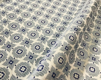 May include: A white fabric with a repeating pattern of blue and gray stylized flowers. The fabric has a subtle texture.