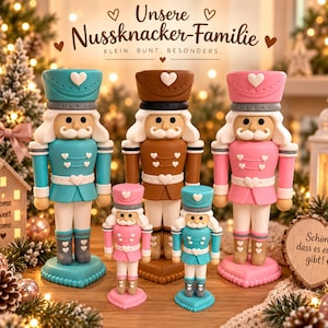 Könnte beinhalten: Fünf Nussknacker-Figuren in Türkis, Braun und Rosa mit weißen Herz-Akzenten. Der Text darüber lautet "Unsere Nussknacker-Familie" und "KLEIN. BUNT. BESONDERS." Ein hölzernes Herzschild rechts trägt den Text "Schön, dass es euch gibt!"