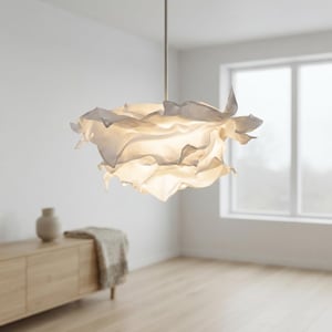 May include: A white pendant light fixture featuring a layered, ruffled shade that resembles the petals of a flower. The shade is suspended from a thin, straight metal rod and emits a soft, warm glow from within its translucent, folded structure.