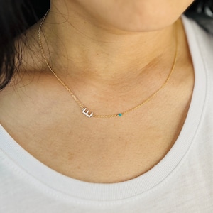 Peut inclure: Un collier en chaîne dorée avec un petit pendentif en forme de lettre "E" et des perles turquoise.