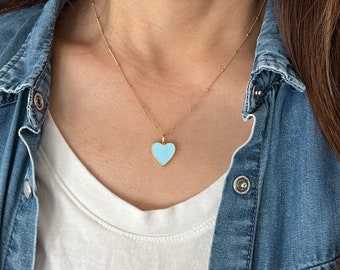 May include: A gold chain necklace with a light blue heart pendant.