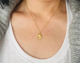 May include: A gold necklace with a four-leaf clover pendant.