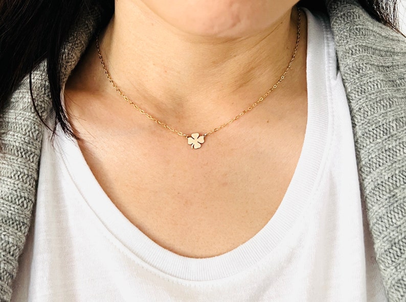 May include: A gold chain necklace with a small four-leaf clover pendant.