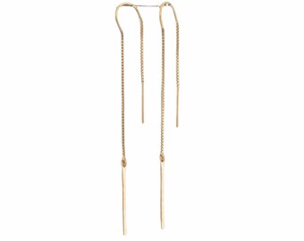 Puede incluir: Un par de pendientes colgantes de oro con cadenas finas y largos acentos rectos de color dorado.