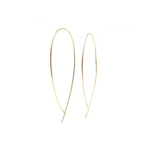 Può includere: Un paio di orecchini a cerchio dorati con un design sottile e delicato in filo.