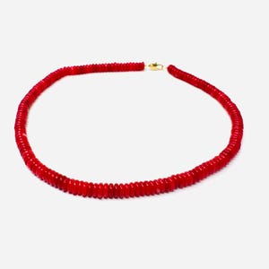 May include: A vibrant red necklace composed of small, round beads. The necklace is secured with a gold-colored clasp. The beads are closely strung together, forming a continuous loop. This jewelry piece is suitable for various occasions.