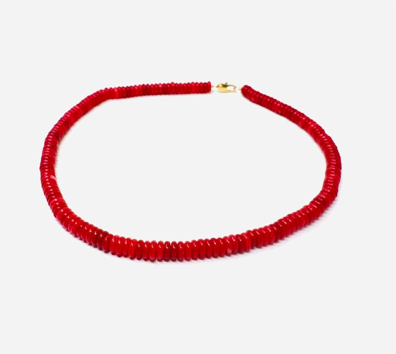 May include: A vibrant red necklace composed of small, round beads. The necklace is secured with a gold-colored clasp. The beads are closely strung together, forming a continuous loop. This jewelry piece is suitable for various occasions.