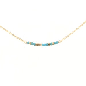 May include: A delicate gold chain necklace with a row of small turquoise blue beads and gold spacers.