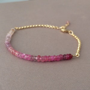 May include: A delicate gold chain bracelet with a gradient of pink sapphires. The bracelet is adjustable with a lobster clasp.
