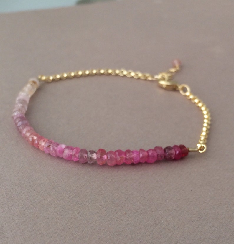 May include: A delicate gold chain bracelet with a gradient of pink sapphires. The bracelet is adjustable with a lobster clasp.