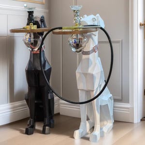 May include: Two decorative dog-shaped tables, one black and one white, with a geometric design. Each dog supports a round table top with a glass globe and a decorative glass piece. A black hose connects the two tables.