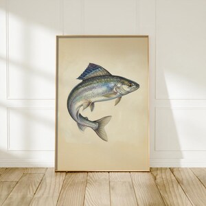 Peut inclure: Une impression d'art mural verticale encadrée représentant une illustration détaillée d'un poisson aux écailles irisées bleues, argentées et grises. Le poisson est représenté en mouvement sur un fond beige clair uni dans un cadre doré fin.