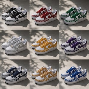 May include: A collection of nine low-top sneakers in various colors, including black, red, green, gray, yellow, purple, navy, tan, and blue. Each sneaker features a white base with a colored swoosh, matching colored laces, and intricate white paisley-style floral patterns on the toe, heel, and side panels, set against a white rubber sole.