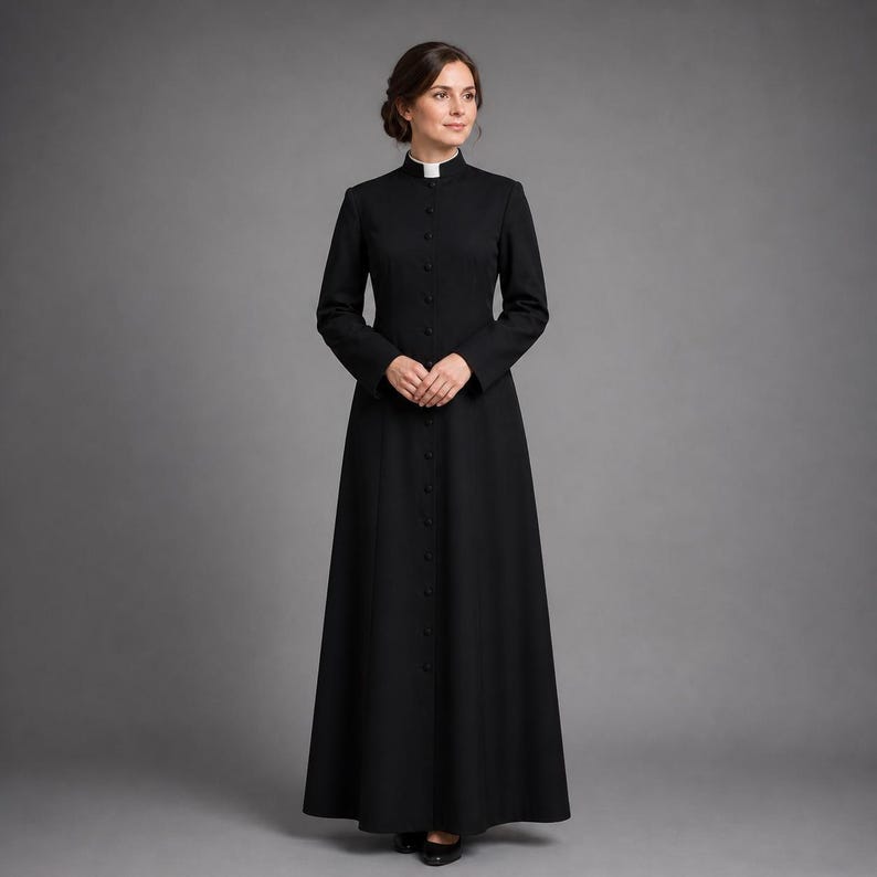 May include: A long, black dress with a high, white collar and long sleeves. The dress is buttoned down the front and has a flowing skirt. The woman is wearing black shoes.