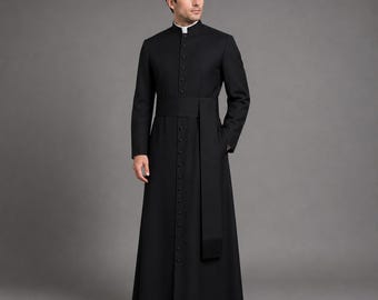 May include: A black cassock with a mandarin collar and a row of buttons down the front. The long-sleeved garment features a matching sash and is worn over a white clerical shirt. The cassock is a traditional garment often worn by clergy.