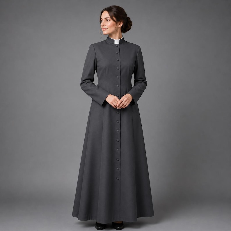 May include: A long, charcoal gray dress with a high, white collar and long sleeves. The dress features a row of buttons down the front and a flared skirt. The woman is wearing black shoes. The dress is a classic, formal style.