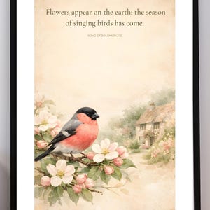May include: A framed watercolor print featuring a red, black, and gray bird perched on a flowering branch. The background shows a quaint cottage and the text "Flowers appear on the earth; the season of singing birds has come."