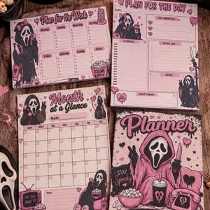 May include: A set of stationery featuring a ghost-themed character in pink and black. The items include a weekly planner, a daily planner, a monthly calendar, and a notebook cover with text including Plan for the Week, Plan for the Day, Month at a Glance, Planner, Stay Spooky, and Slay Your Goals.