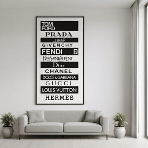 May include: A framed black and white print featuring the logos of luxury fashion brands such as Tom Ford, Prada, Givenchy, Fendi, and others. The brands are listed in a vertical arrangement on a white background.