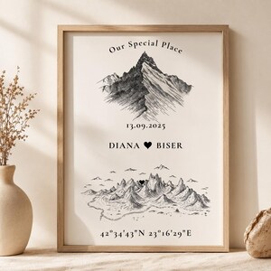 May include: A framed vertical print featuring a black ink mountain illustration, the text "Our Special Place", the date "13.09.2025", the names "DIANA" and "BISER" separated by a heart icon, a second mountain landscape, and coordinates.