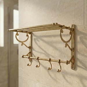 Puede incluir: Estante de baño de metal dorado con toallero y cinco ganchos. El estante tiene una parte superior rectangular con barras horizontales y adornos decorativos en los laterales. Montado en una pared de azulejos claros.