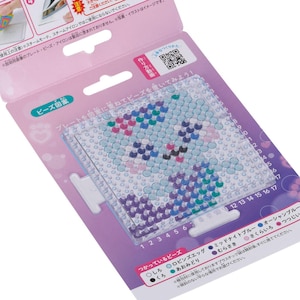 May include: A craft kit with a clear plastic pegboard featuring a cartoon character design made of colourful beads. The kit includes a pink and white cardboard backing with Japanese text and a QR code.