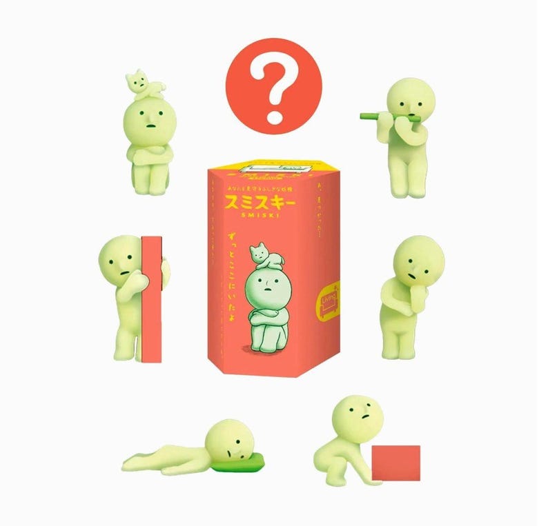 a collection of seven small, green figurines arranged in a circular pattern around a large red box with Japanese text.