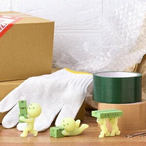 a variety of objects, including a cardboard box, a white glove, a green tape roll, and several small figurines, all arranged on a wooden surface.