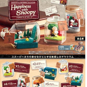 Puede incluir: Colección de figuras de terrario Snoopy & Friends en tarros de cristal. Cada tarro presenta una escena diferente con Snoopy, Charlie Brown y Woodstock. Los terrarios están etiquetados con frases como "Happiness is... Warm Puppy."