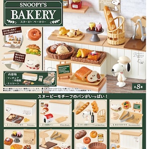 May include: A miniature Snoopy's Bakery playset with bread, pastries, and donuts. The set includes Snoopy figurines and bakery display elements. The packaging includes text in Japanese.