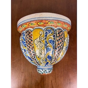 May include: A white ceramic mug with a black handle and the text "But First, Coffee" in a black, handwritten-style font. The mug is on a white surface.