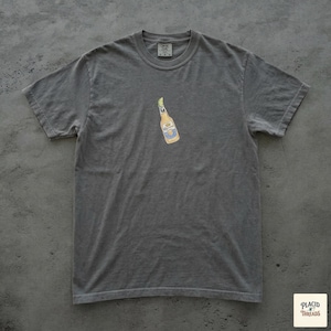 Puede incluir: Una camiseta gris con un peque&ntilde;o gr&aacute;fico de una botella de cerveza. La botella de cerveza es amarilla con detalles azules y blancos. La camiseta tiene cuello redondo y mangas cortas. La etiqueta de la marca es visible en la parte superior de la camiseta.