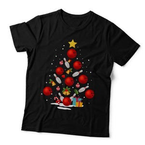 May include: A black short-sleeved t-shirt featuring a graphic of a Christmas tree constructed from red bowling balls, white bowling pins, gold bells, and small gift boxes. A yellow star sits at the top of the tree design, surrounded by white dots.