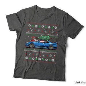 May include: A dark charcoal grey short-sleeve t-shirt featuring a graphic of a blue sports car with a Christmas tree strapped to the roof and Santa Claus in the driver seat, surrounded by a festive pattern of snowflakes, trees, and turbochargers.
