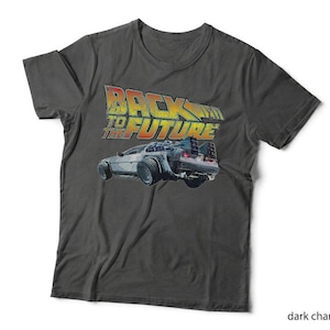 May include: A dark charcoal grey short-sleeve t-shirt featuring a graphic print of the Back to the Future logo in yellow and red, positioned above an illustration of the silver DeLorean time machine car viewed from the rear angle.
