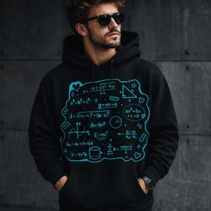 May include: A black hooded sweatshirt featuring a vibrant cyan graphic print on the chest. The design displays various mathematical formulas, geometric shapes, and small heart and star icons arranged in a cluster, including equations like E=mc2.