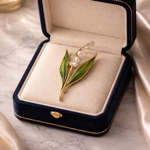 Guldfärgad liljekonvaljbrosch, emaljnål med blommigt blad, kristalldetaljer i vintagestil